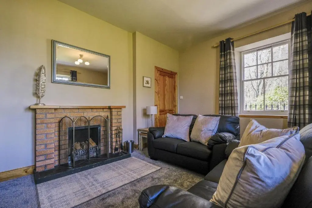 a living room with a couch and a fireplace at Gledfield Estate Holiday Cottages in Lower Gledfield