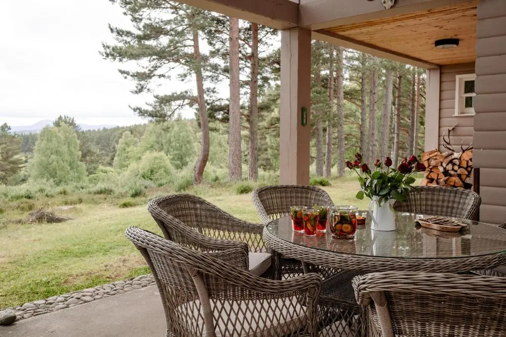 a patio with a table and chairs on a porch at Glencarnie - Seasgair Lodges in Boat of Garten
