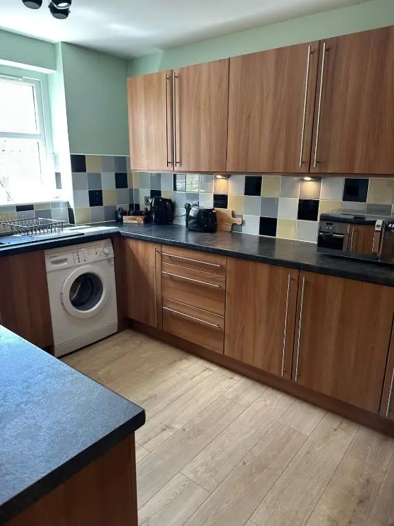 a kitchen with wooden cabinets and a washing machine at The Inver Nest in Inverness