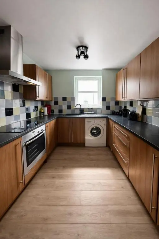 a large kitchen with wooden cabinets and a dishwasher at The Inver Nest in Inverness