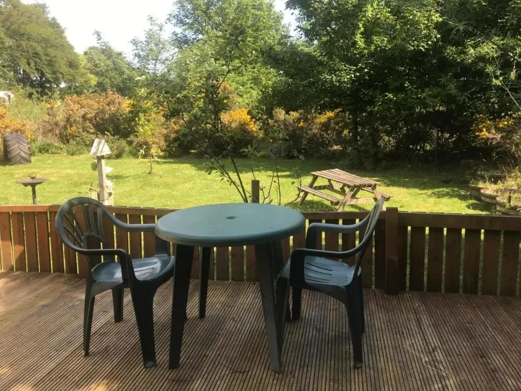 a table and two chairs on a deck at Cosy Apartment in the Highlands in Muir of Ord