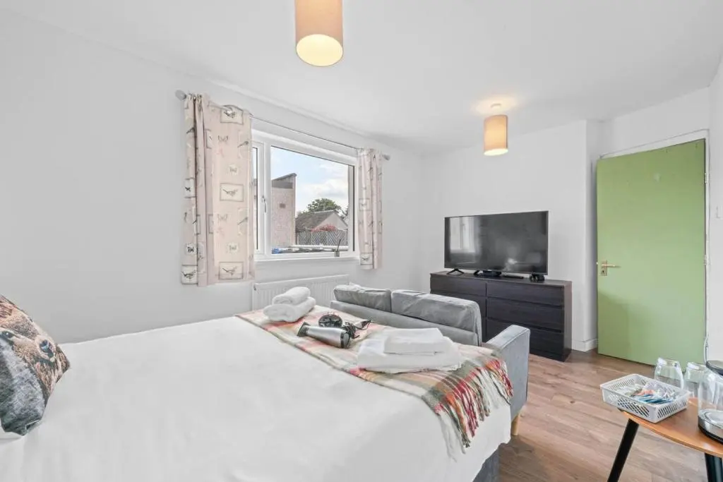 a white bedroom with a bed and a television at Cloudhowe Cottage Ensuite Rooms & Studio Inverness in Inverness