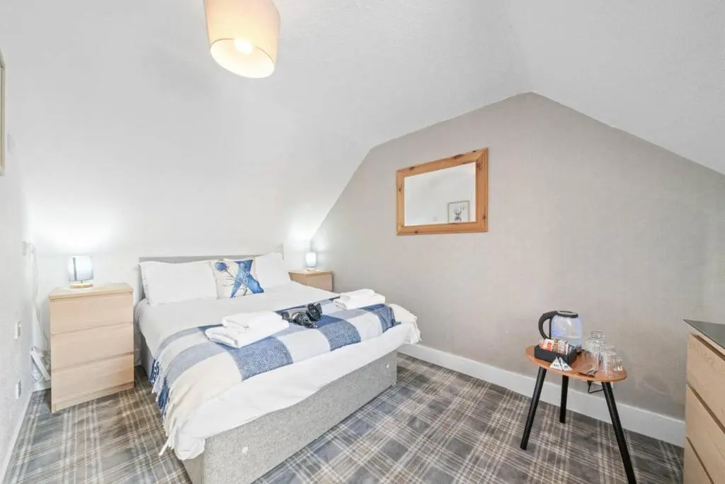 a bedroom with a bed and a mirror on the wall at Cloudhowe Cottage Ensuite Rooms & Studio Inverness in Inverness