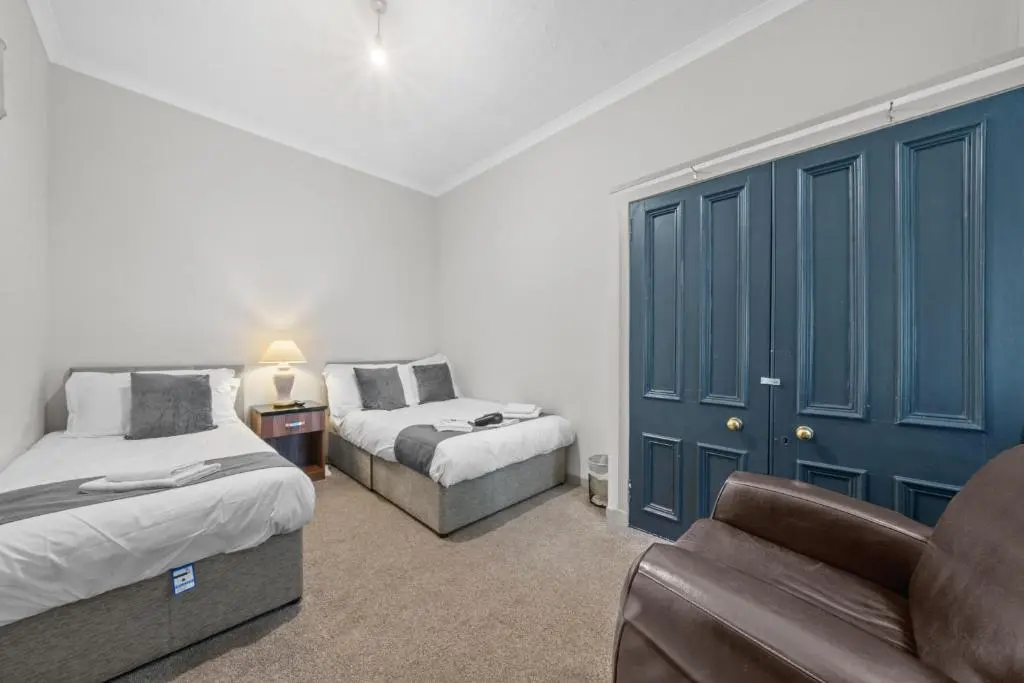 a bedroom with two beds and a couch and a chair at Central Inverness Hideaway - 2 Bedroom Flat in Inverness