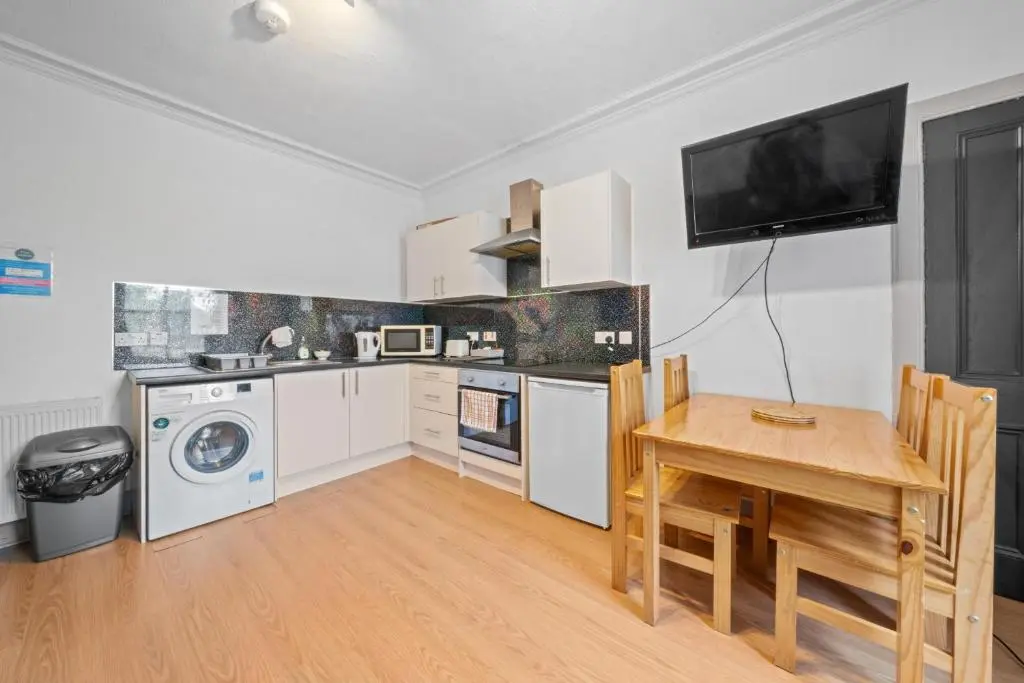 a kitchen with a table and a tv on the wall at 2 Bedroom Inverness Apartment - Perfect Location in Inverness