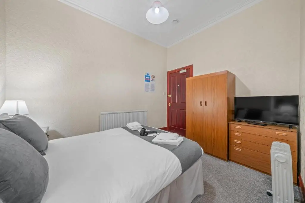 a hotel room with a bed and a television at Struy Guest House - Inverness in Inverness