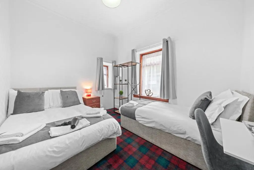 a living room with two beds and a window at Struy Guest House - Inverness in Inverness
