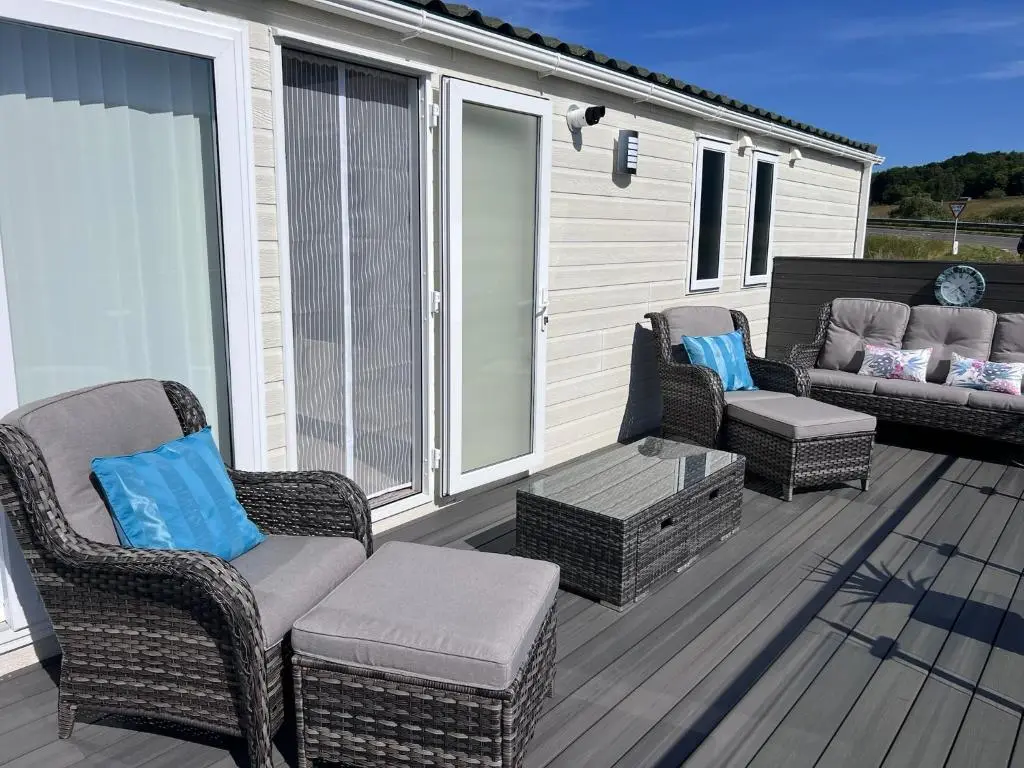 a deck with wicker chairs and a coffee table at Drift Lodge in Tain