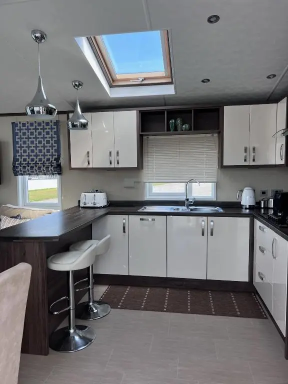 a kitchen with white cabinets and a sink and a window at Drift Lodge in Tain