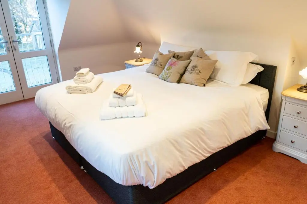 a bedroom with a large bed with towels on it at Old Coach House in Braemar
