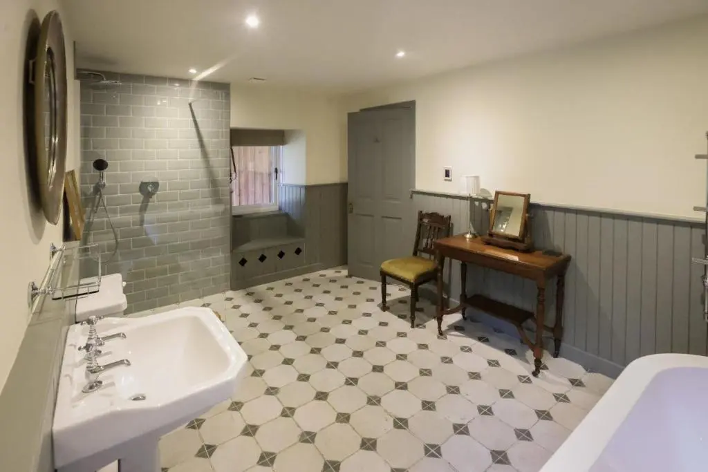 a bathroom with a sink and a desk and a tub at Relugas Mill in Forres