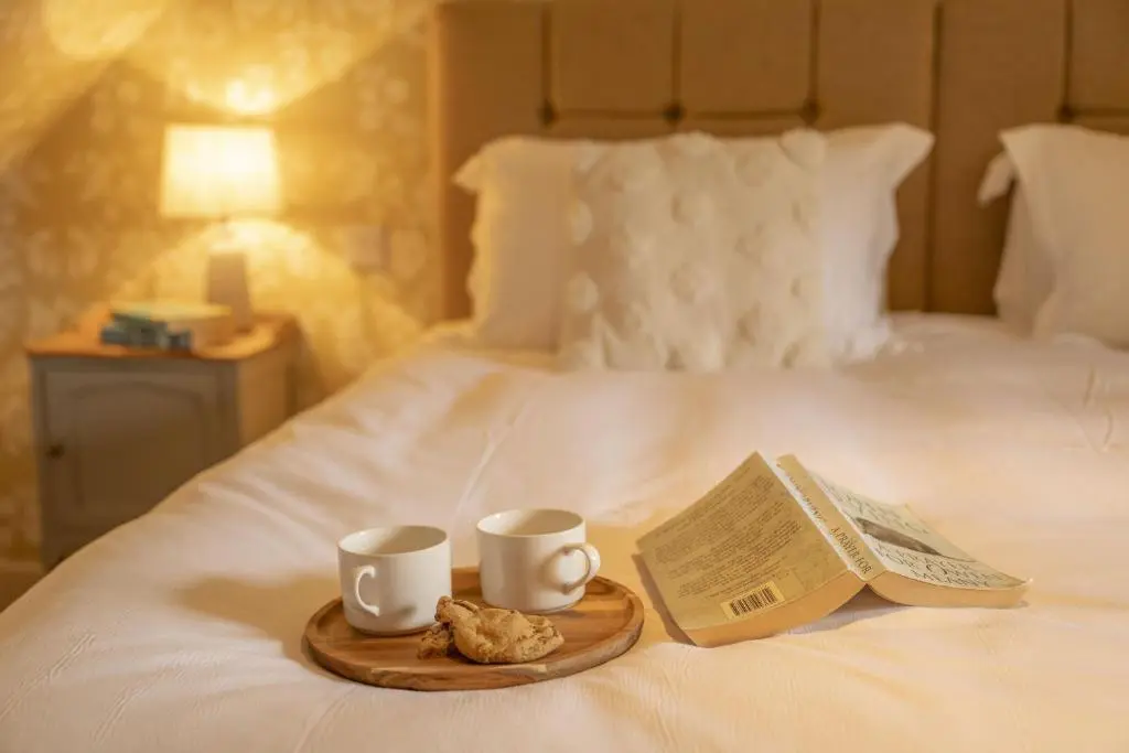 a tray with two cups and a newspaper on a bed at Laggandhu in Nethy Bridge