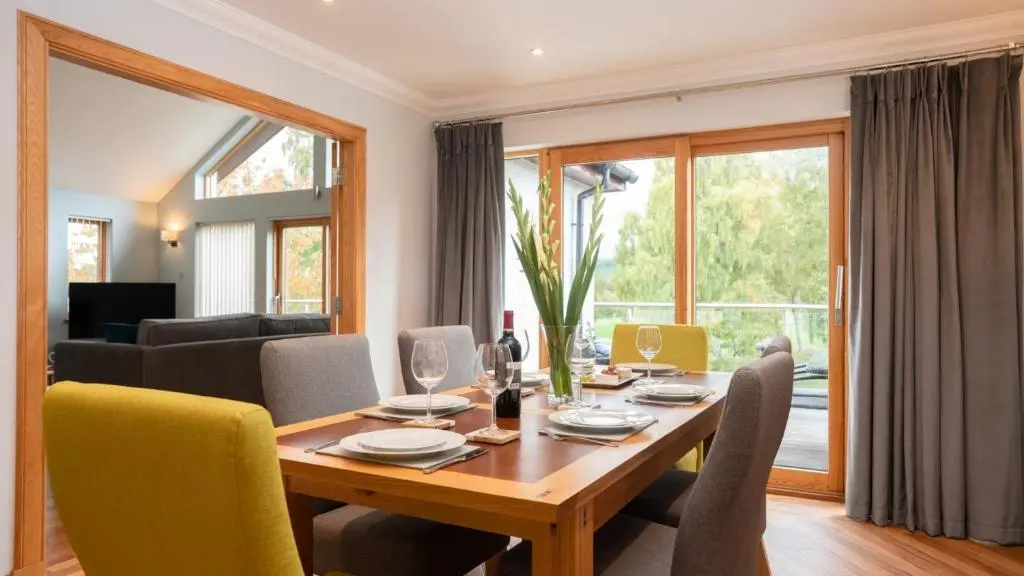 a dining room with a wooden table and yellow chairs at Coorie Lodge in Aviemore