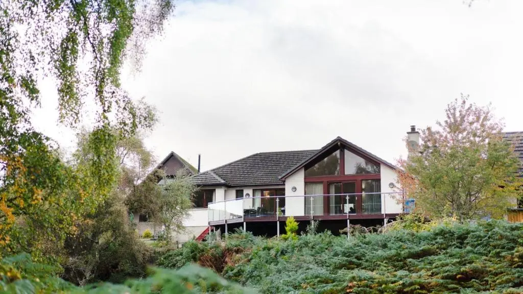 a house with a balcony on top of a hill at Coorie Lodge in Aviemore