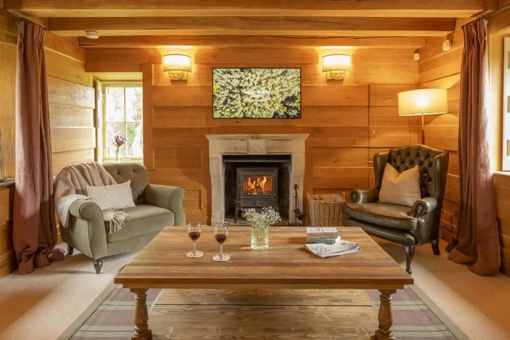 a living room with a table and a fireplace at Drum Cottage in Nethy Bridge