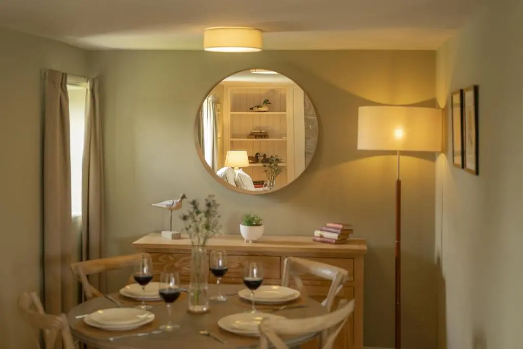 a dining room with a table and a mirror at Ellon Cottage in Nethy Bridge