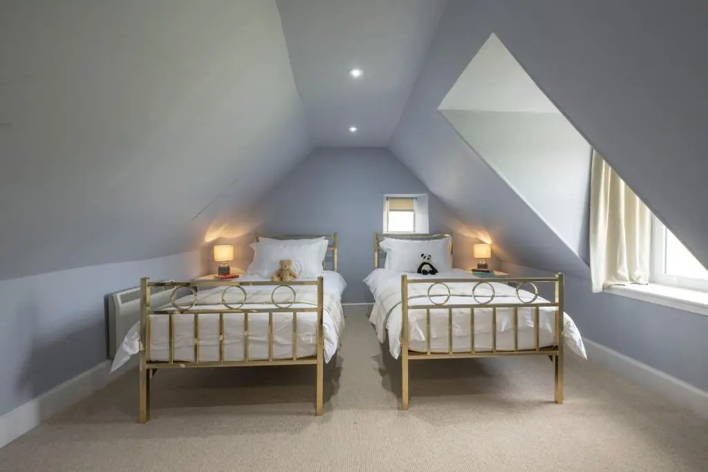 a attic bedroom with two beds and two lamps at Ellon Cottage in Nethy Bridge
