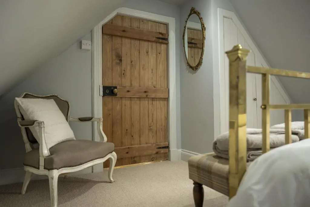 a bedroom with a bed and a chair and a mirror at Ellon Cottage in Nethy Bridge