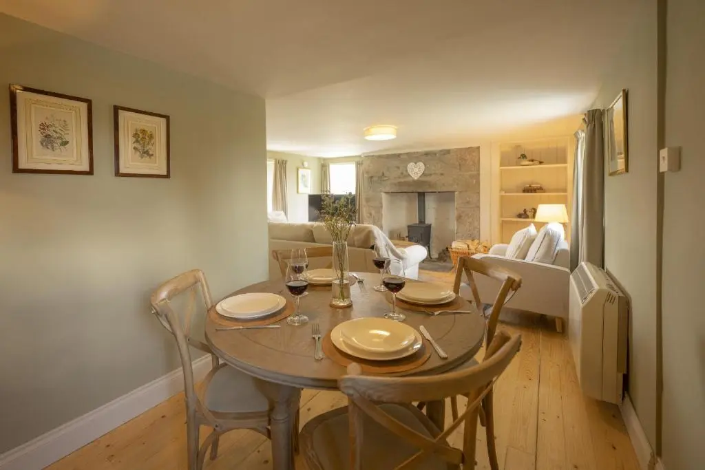 a dining table and chairs in a living room at Ellon Cottage in Nethy Bridge