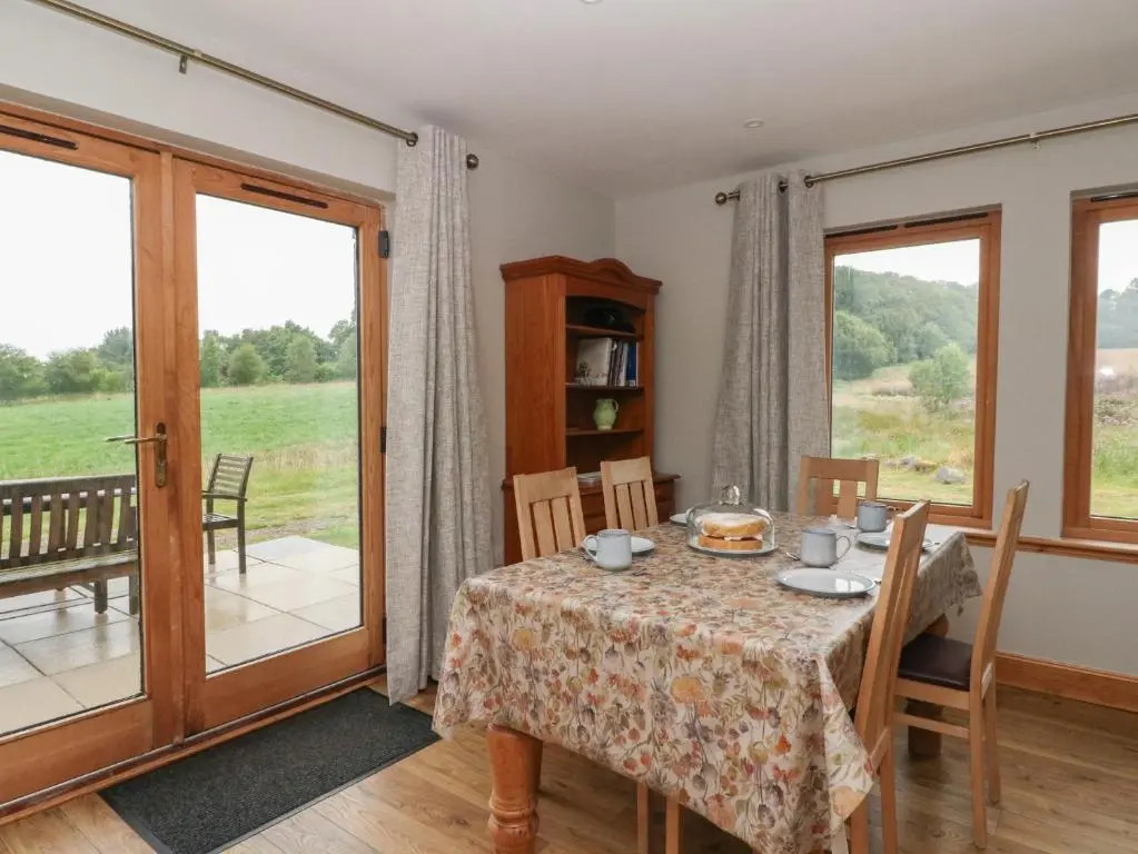 a dining room with a table and views of a field at Taffs Barn in Fortrose