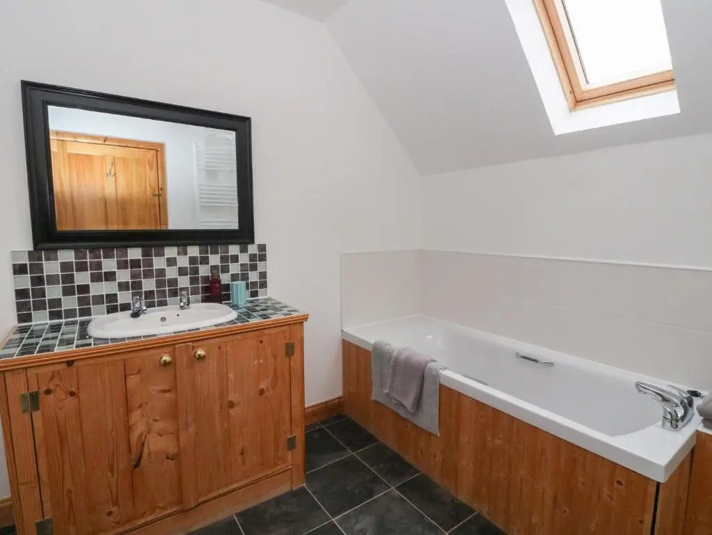 a bathroom with a bath tub and a sink at Taffs Barn in Fortrose