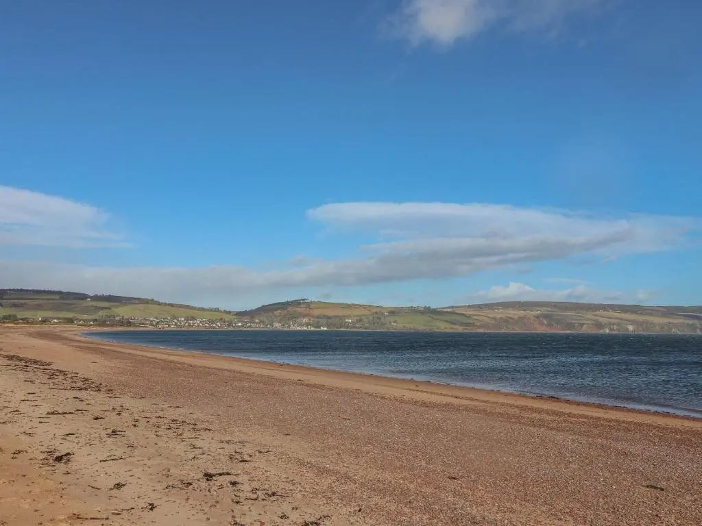 a sandy beach with water and hills in the background at Taffs Barn in Fortrose