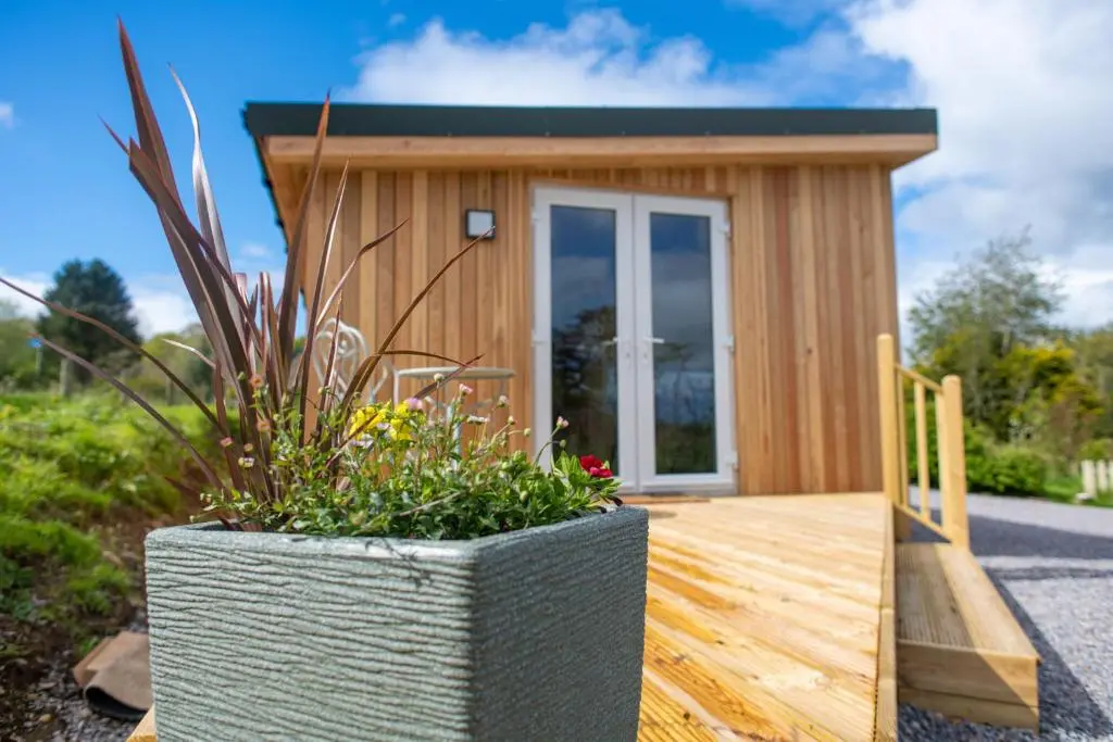 a tiny house with a large planter on a wooden deck at The Drey Inchberry