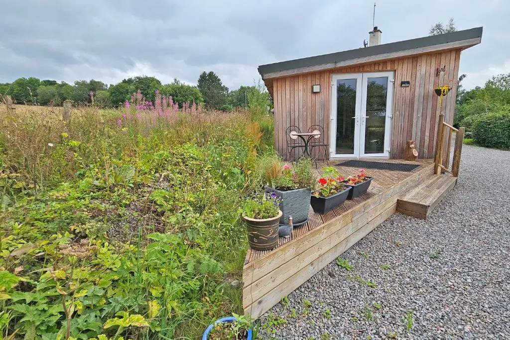 a small wooden building with plants in a field at The Drey Inchberry