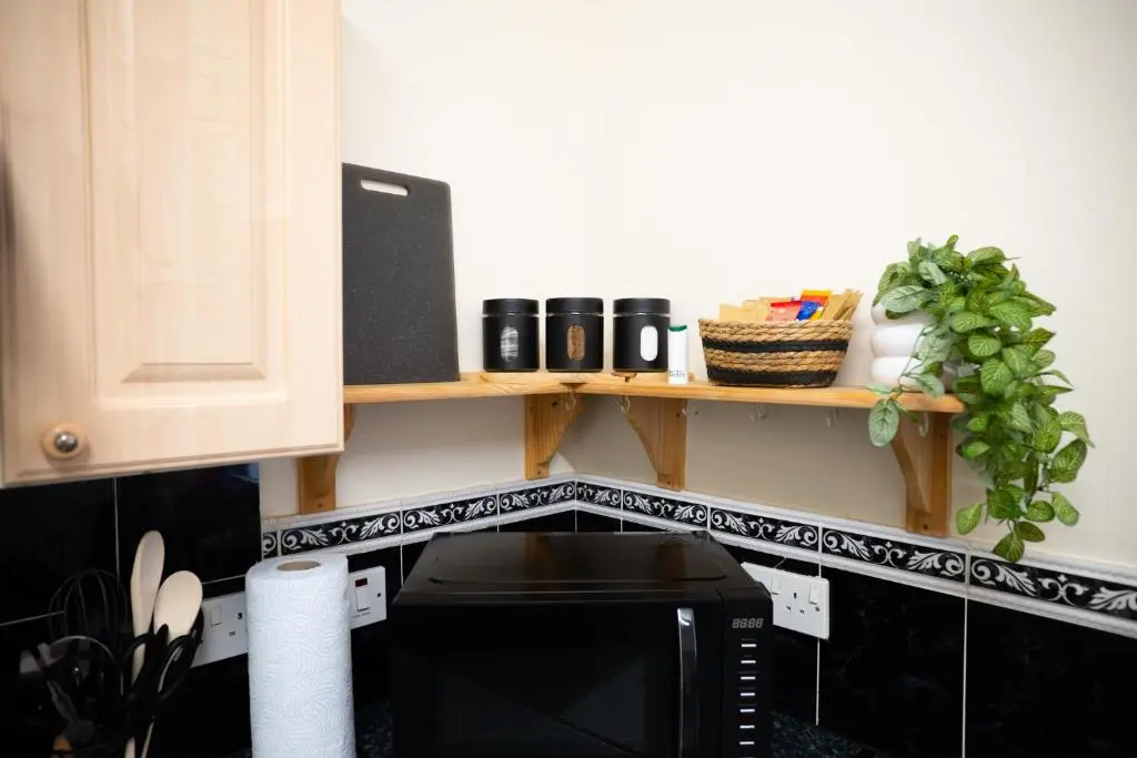 a kitchen counter with a shelf above a microwave at Innes Street Apartment in Inverness