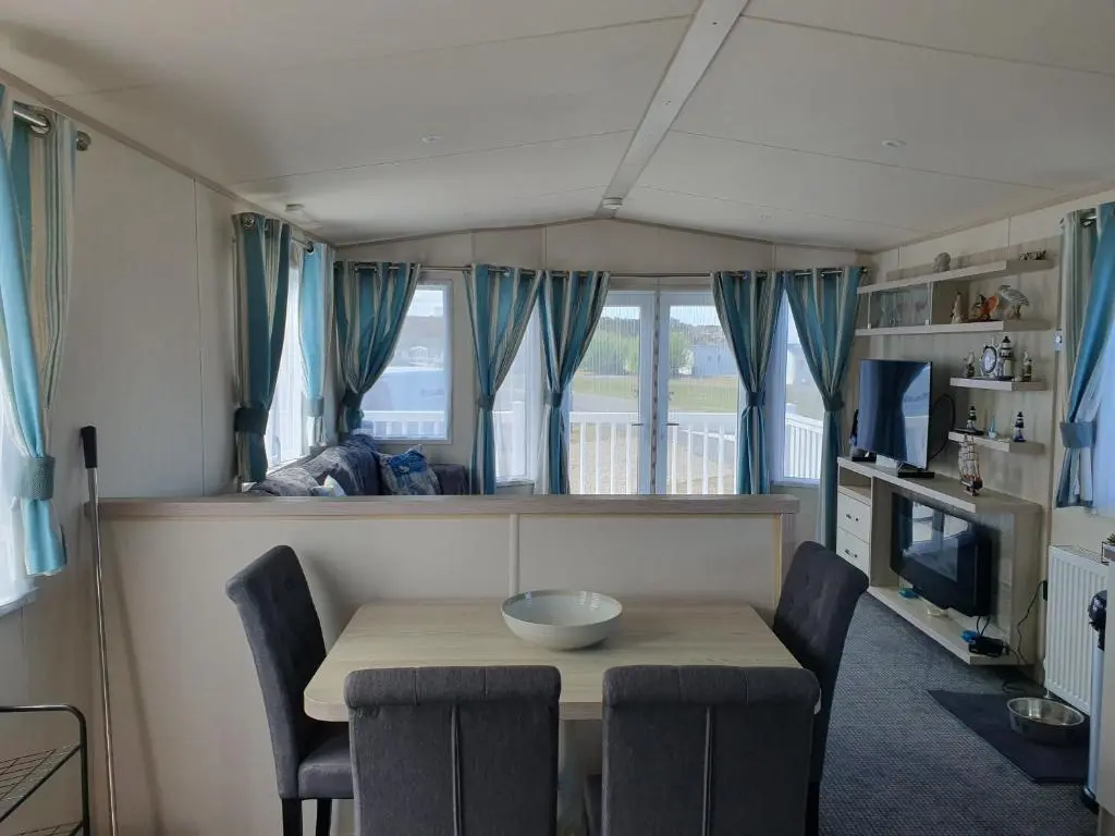 a dining room with a table and chairs and a television at H26atsilversands in Lossiemouth