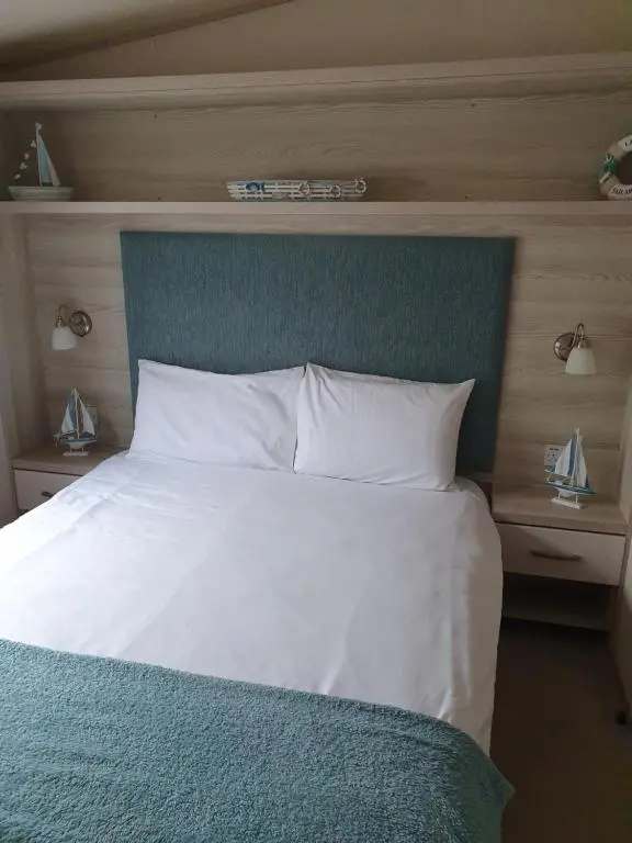 a large white bed with a blue headboard and white pillows at H26atsilversands in Lossiemouth