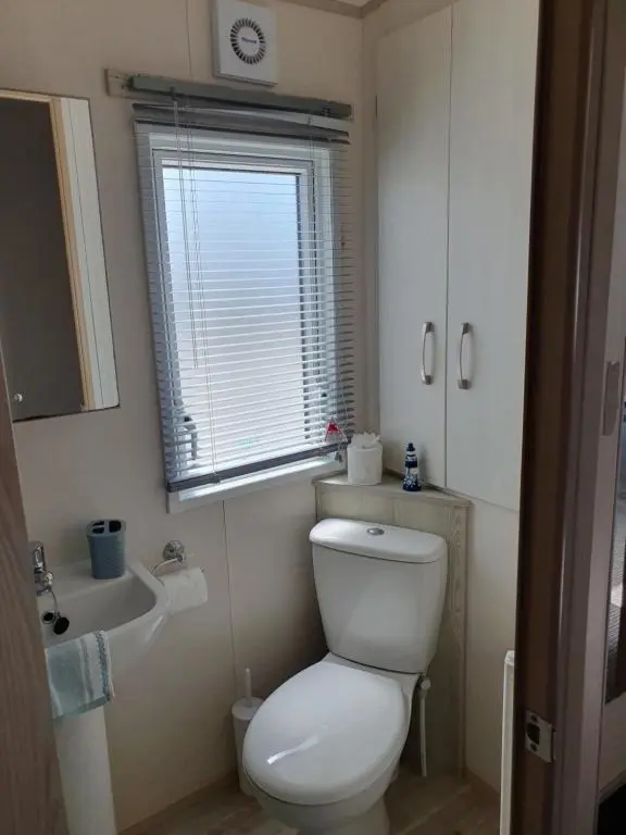 a bathroom with a toilet and a sink and a window at H26atsilversands in Lossiemouth