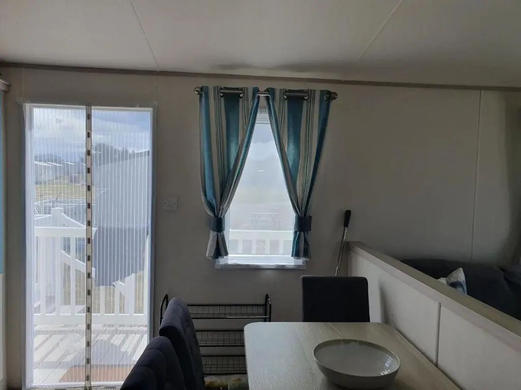 a living room with a table and a window at H26atsilversands in Lossiemouth