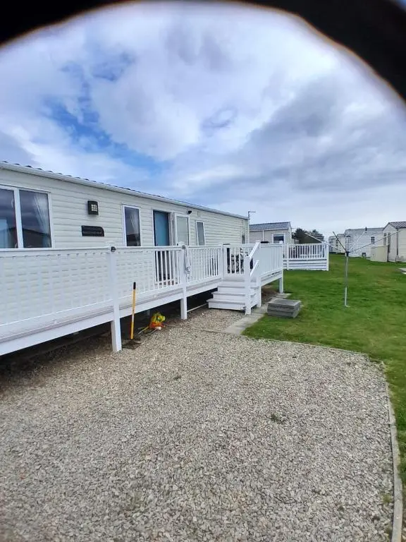 a white mobile home with a white fence at H26atsilversands in Lossiemouth