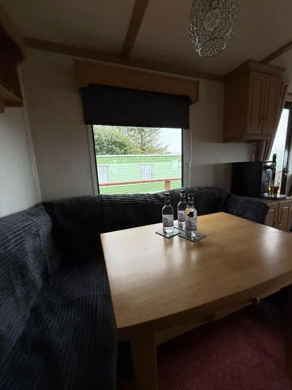 a living room with a wooden table and a couch at Caravan in Banff