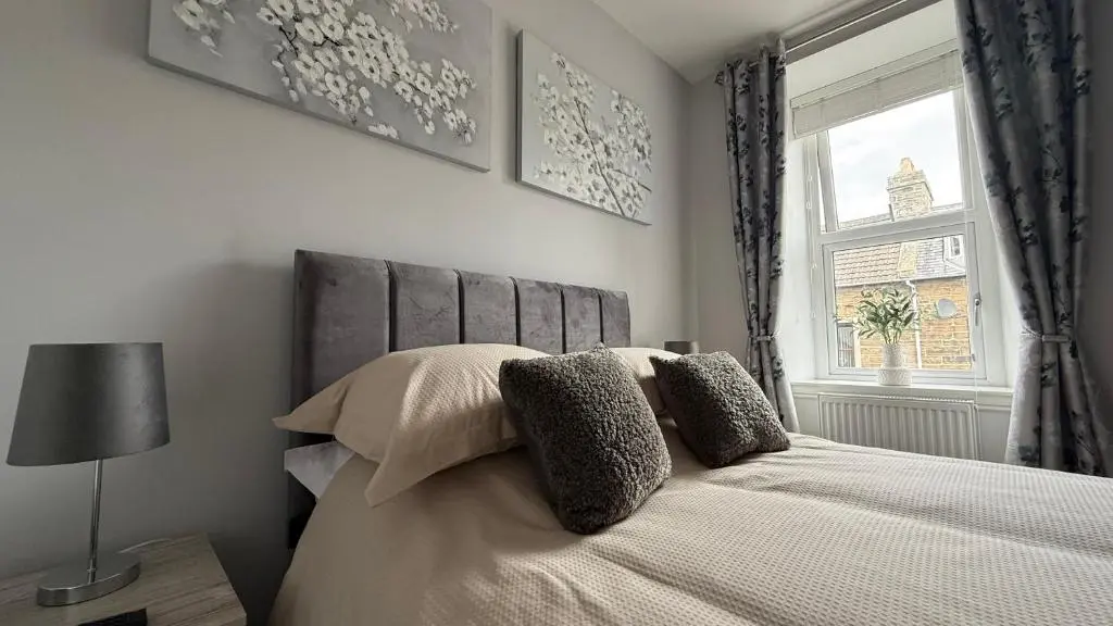 a bedroom with a bed with pillows and a window at The Bakehouse - by Caithness Luxury Apartments NC500 - 5 Bedroom Luxury Holiday Home - Sleeps Work teams upto 5 & holiday makers upto 10 in Wick
