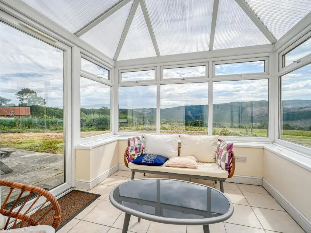 a conservatory with a couch and a glass table at Holiday Home The Manor House by Interhome in Balnain
