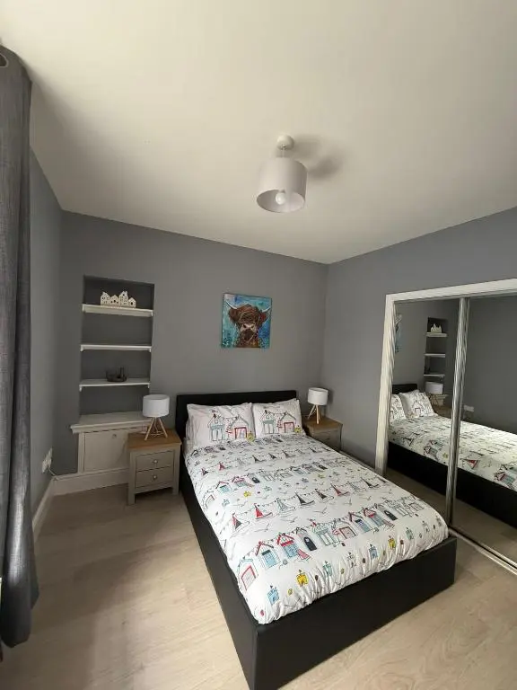 a bedroom with a large bed and a mirror at The Willows in Nairn