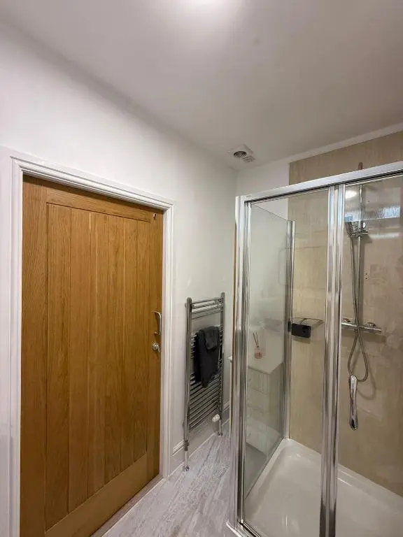 a bathroom with a shower and a wooden door at The Willows in Nairn