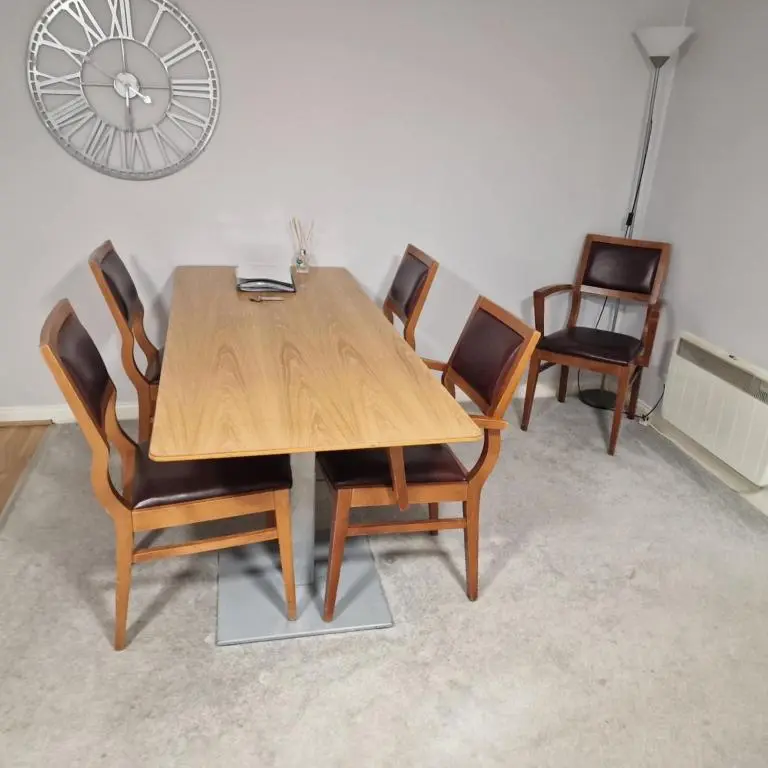 a dining room table with chairs and a clock on the wall at Black Isle Holiday Apartments Avoch in Avoch