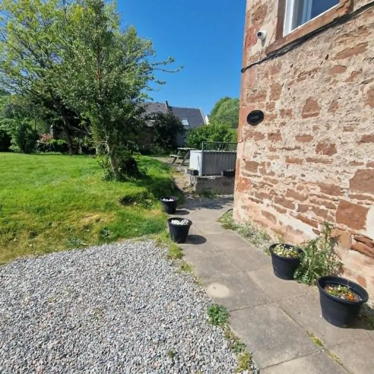 a stone house with three pots on the side of it at Black Isle Holiday Apartments Avoch in Avoch