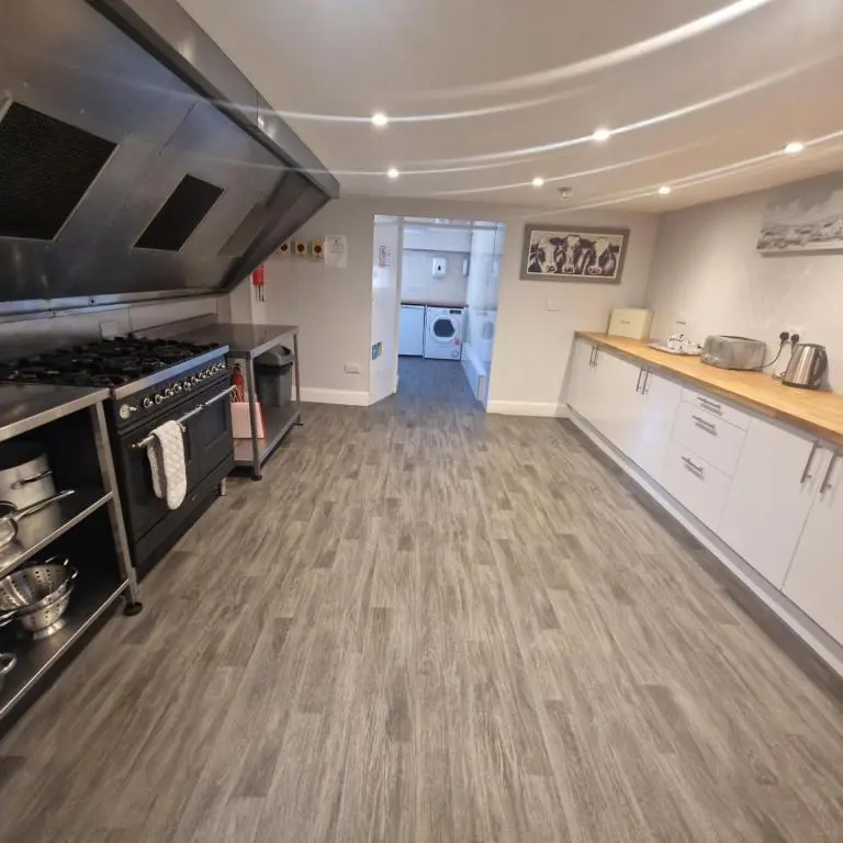 a large kitchen with white cabinets and a wooden floor at Black Isle Holiday Apartments Avoch in Avoch