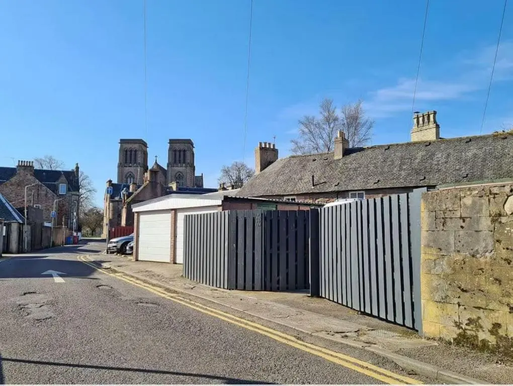 an empty street with houses and a fence at 1 Bedroom Alexander Cottage-Free Parking in Inverness