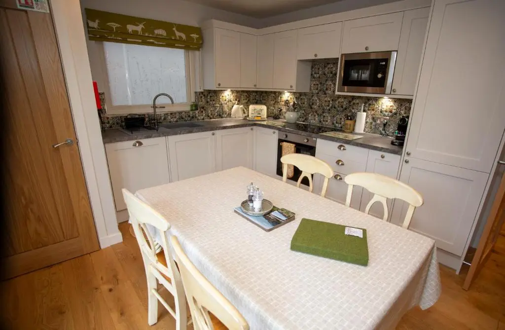 a kitchen with a table and chairs and a kitchen with white cabinets at Harris House in Inverness