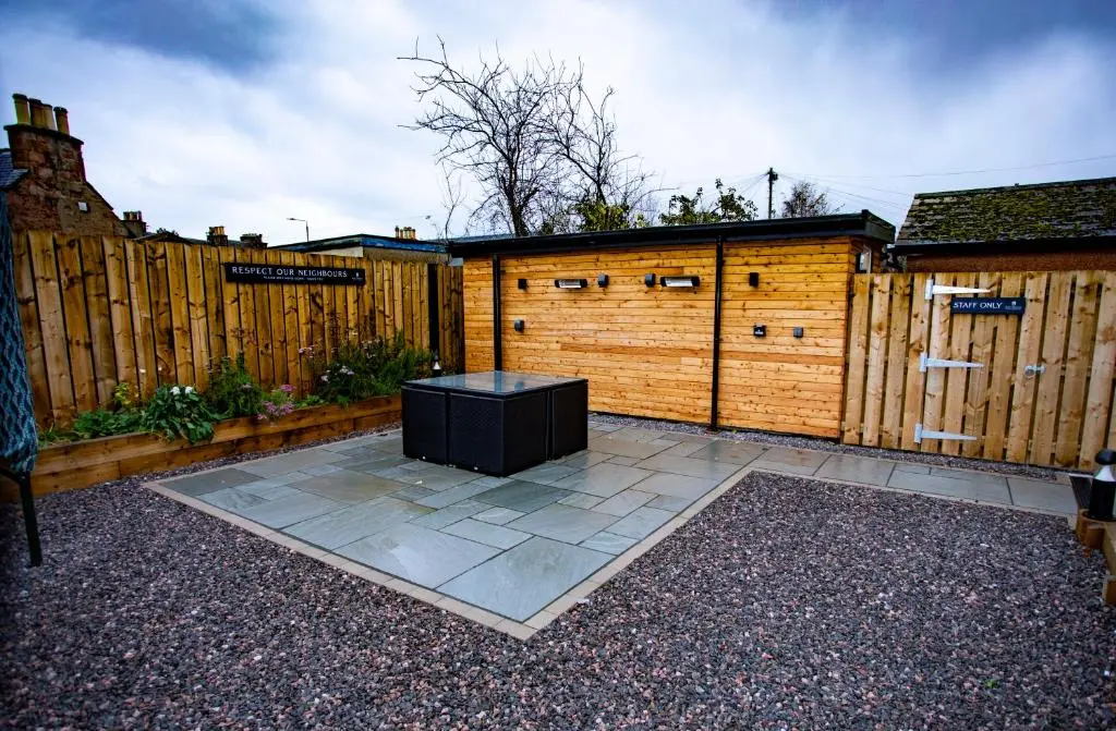 a backyard with a wooden fence and a black table at Harris House in Inverness