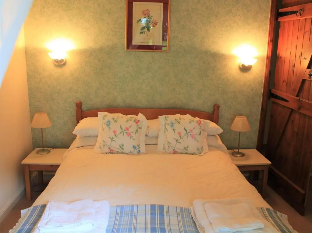 a bedroom with a bed with pillows and two lamps at St Brandon House Country Cottages in Boyndie