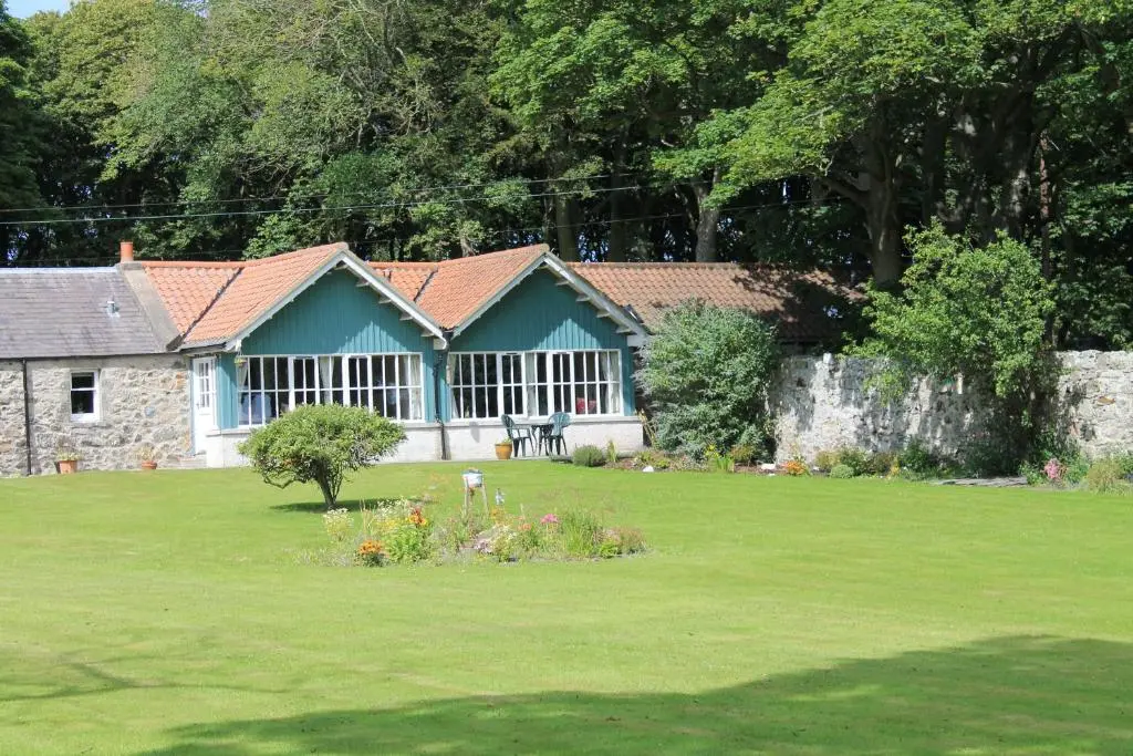 a house in a yard with a green lawn at St Brandon House Country Cottages in Boyndie