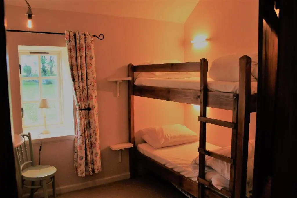 a bedroom with two bunk beds and a window at St Brandon House Country Cottages in Boyndie