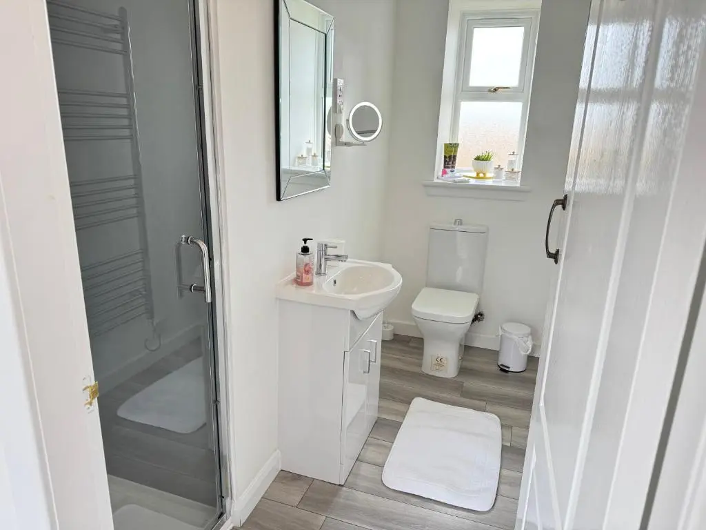 a white bathroom with a shower and a sink at Altons Bothy Guest House
