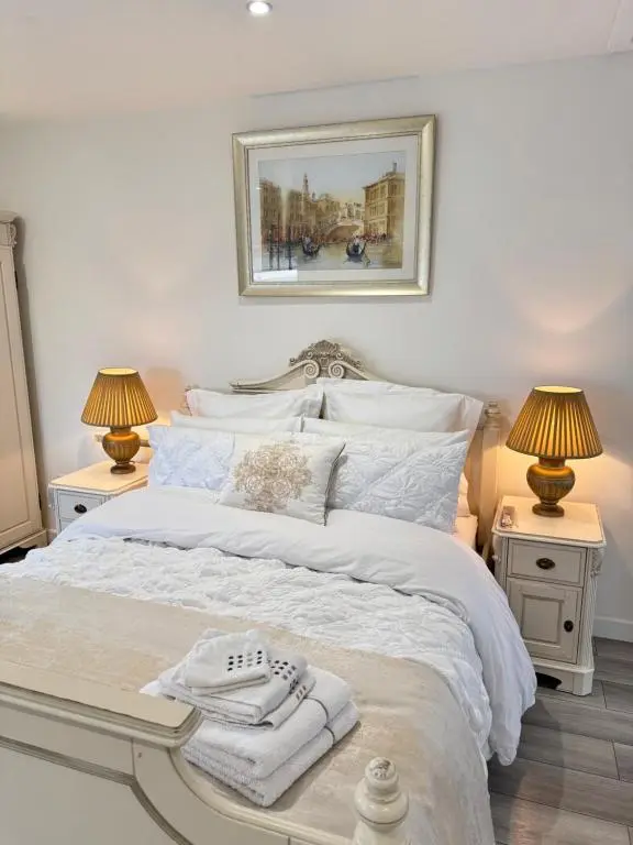 a bedroom with a white bed with two lamps at Altons Bothy Guest House